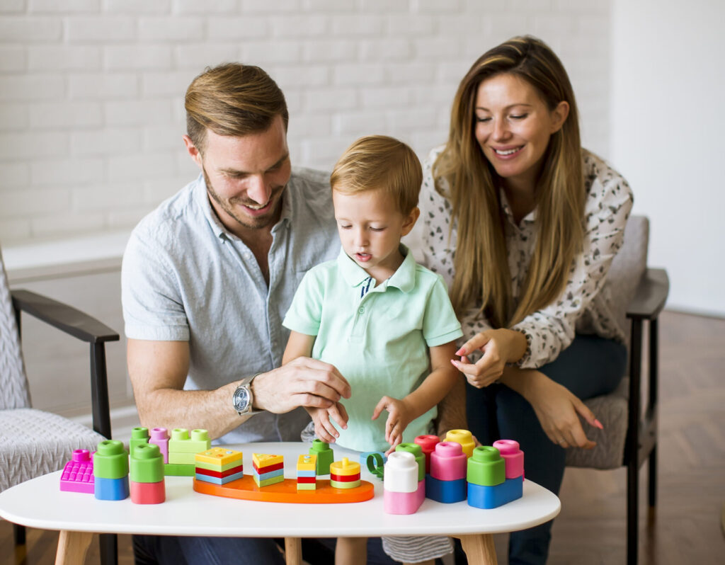 Família brincando junta no chão da sala com jogos educativos