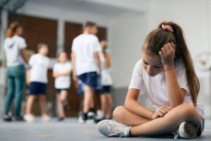 criança isolada em ambiente escolar enquanto outras interagem blog espaço arima